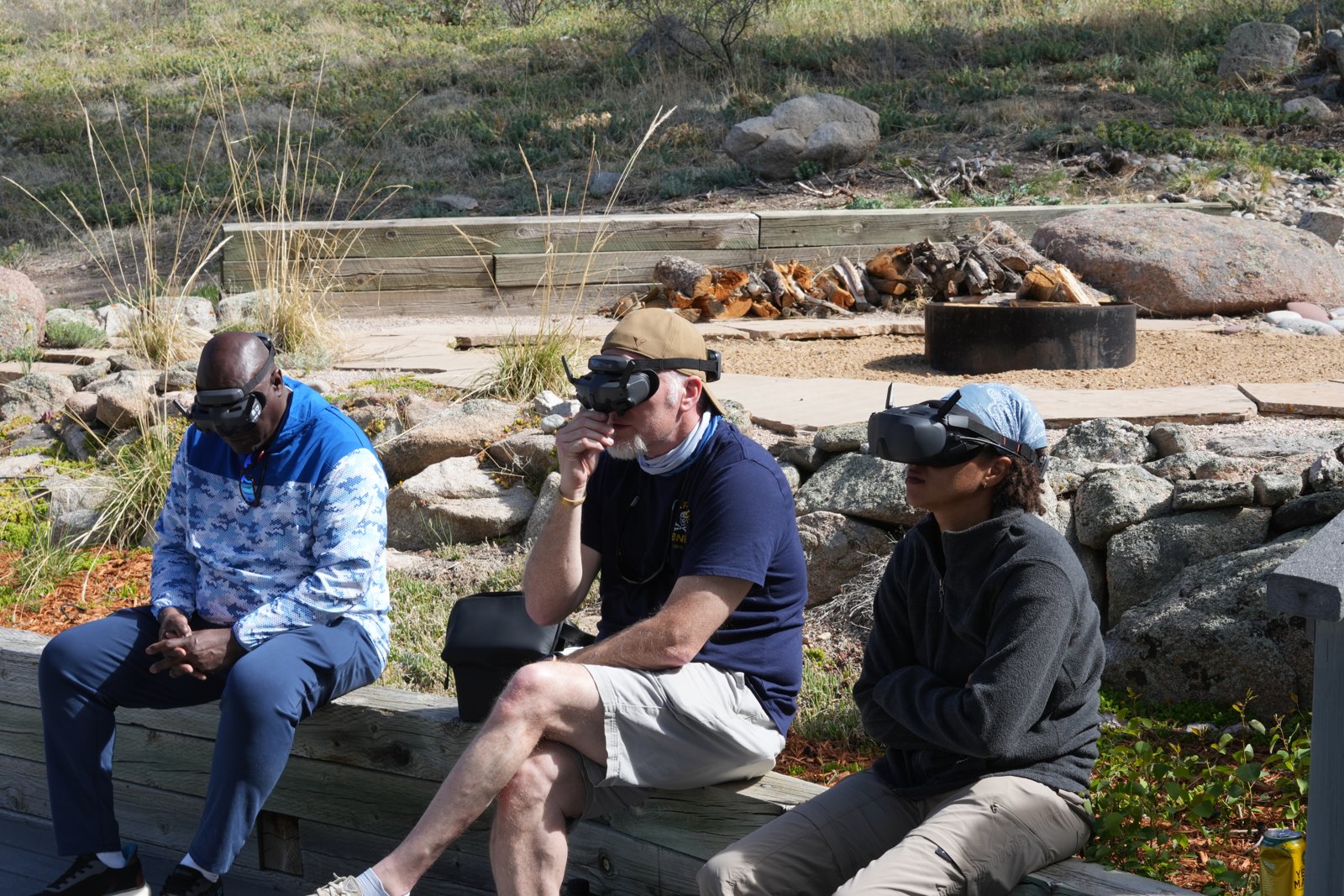 A group of friends wearing DJI Goggles 3 together outdoors, watching the same drone flight
