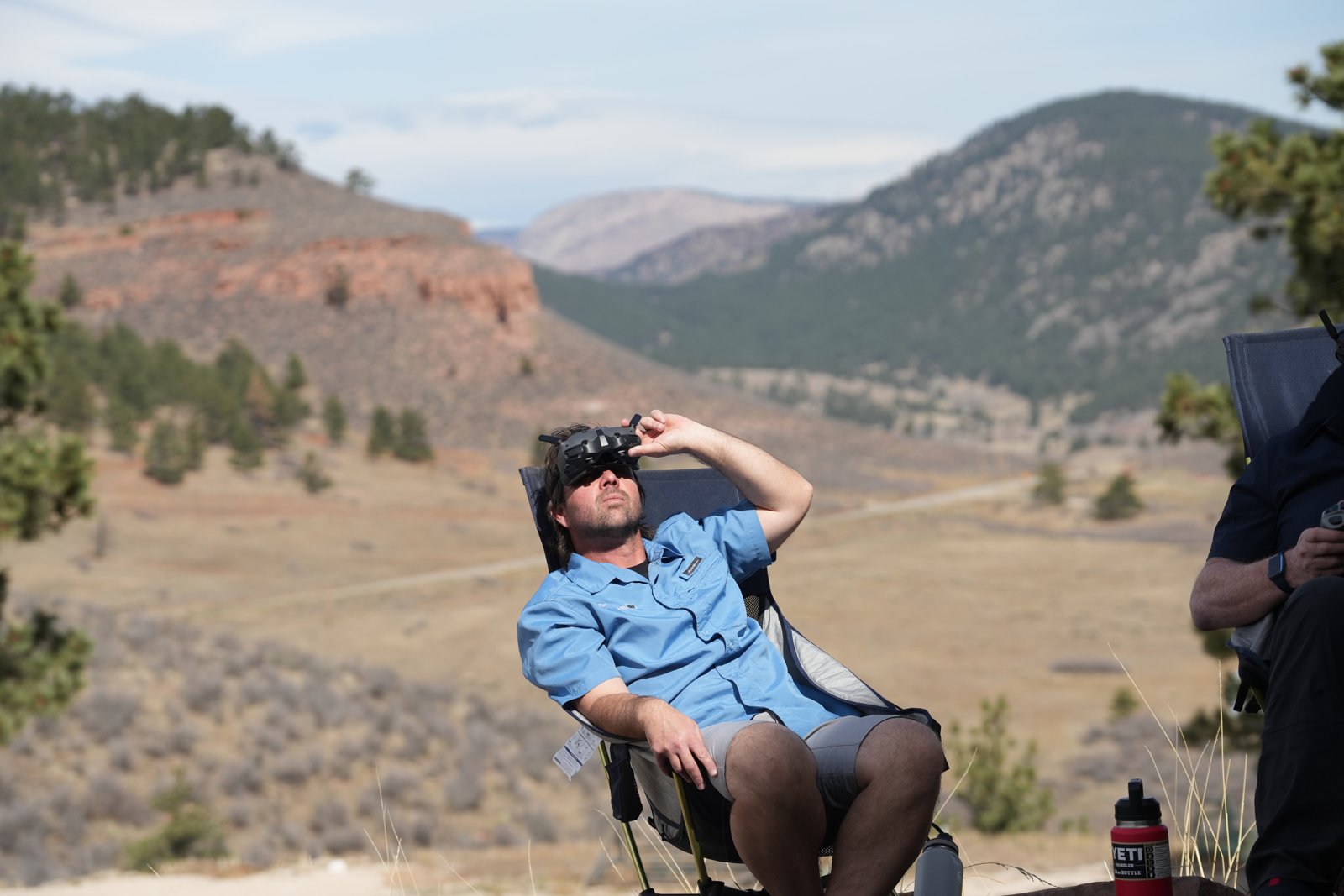 Friends in goggles watching a DJI Avata 2 flight with a mountain landscape behind them