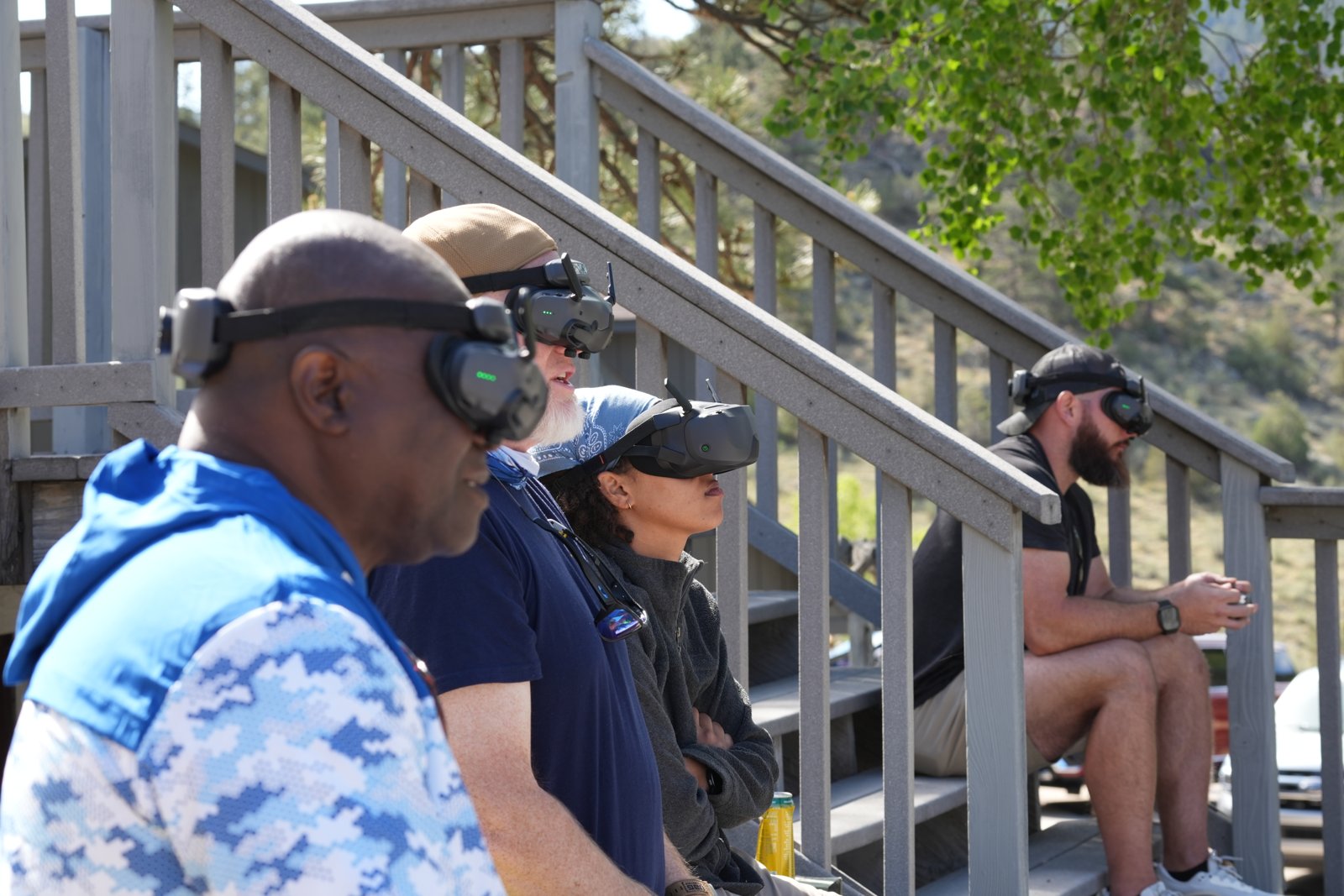 A group of friends on a set of stairs wearing DJI Goggles 3 together to watch a shared drone flight