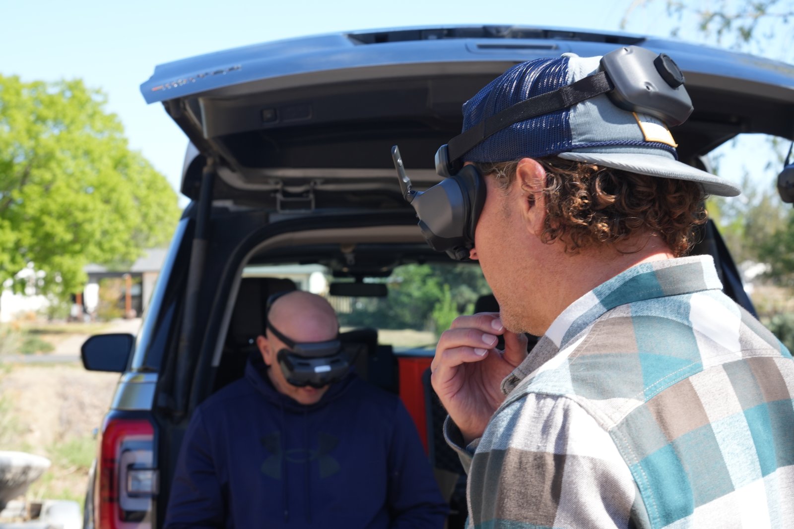 Friends wearing goggles at a tailgate watching a shared DJI Avata 2 flight