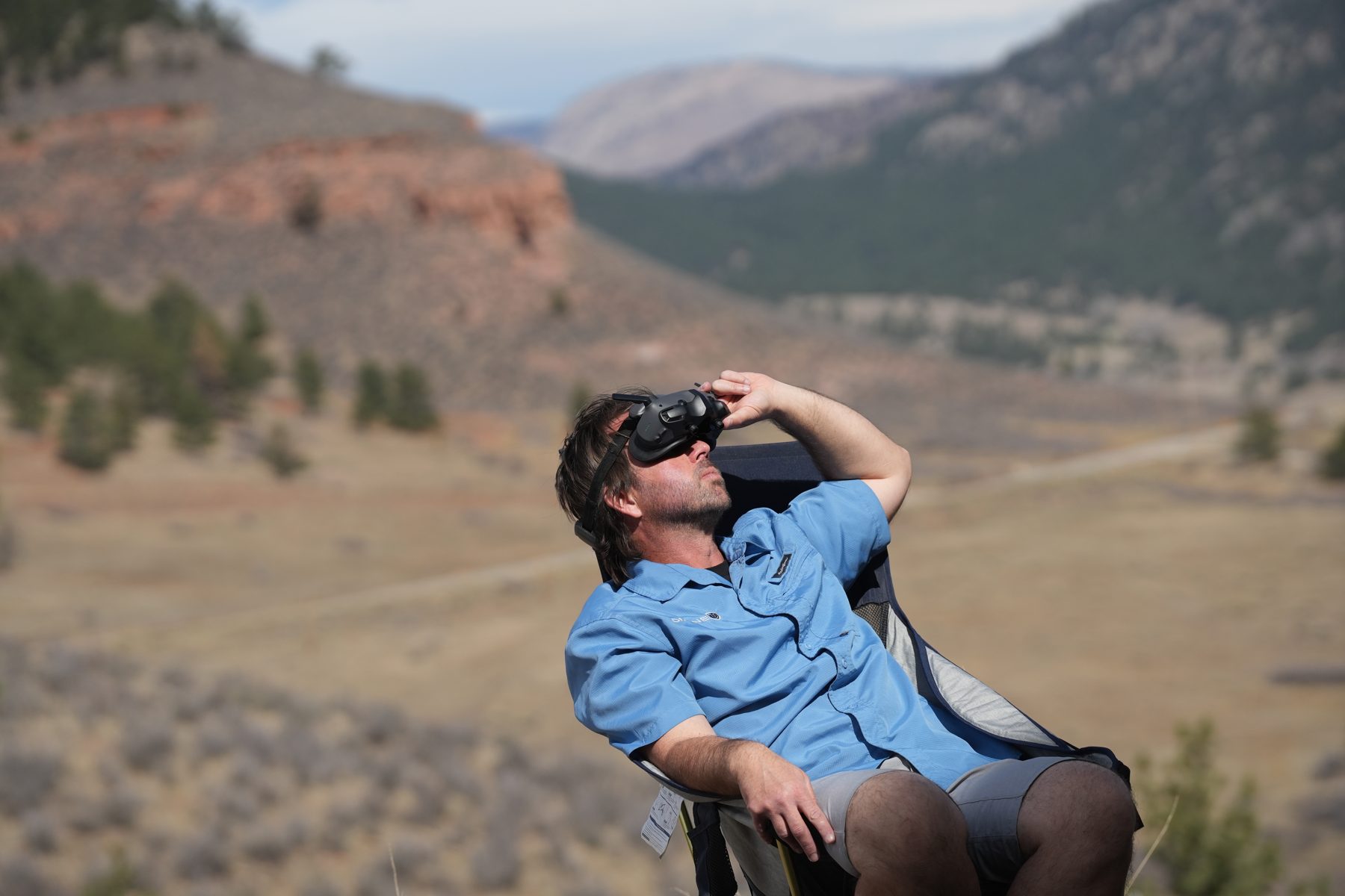 FPV pilot flying the DJI Avata 2 with goggles in the mountains