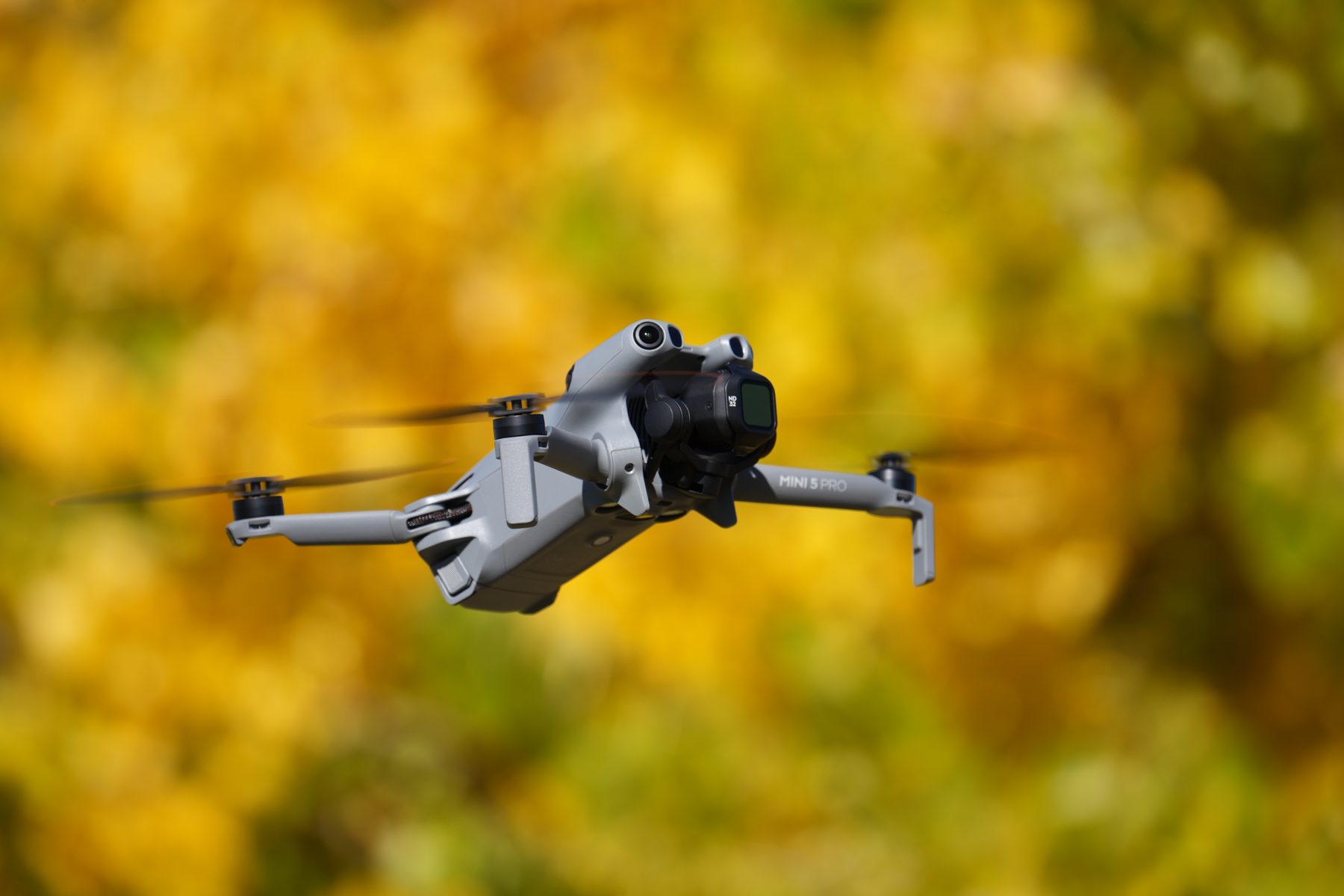 DJI Mini 5 Pro flying in front of fall foliage