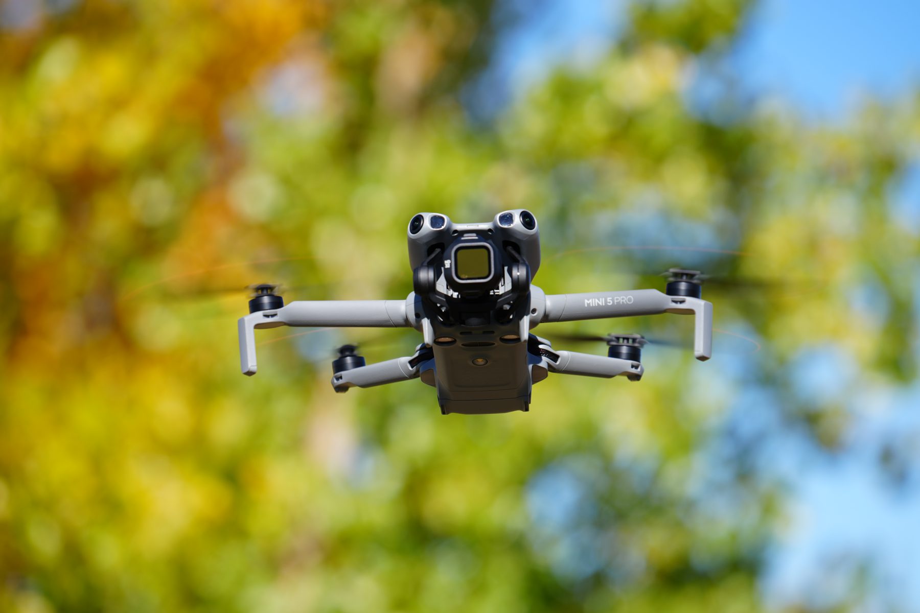 DJI Mini 5 Pro flying in front of fall foliage