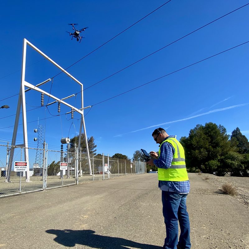 FAA Section 2209 - pilot in a safety vest flying a drone beside a high-voltage substation - Drone U