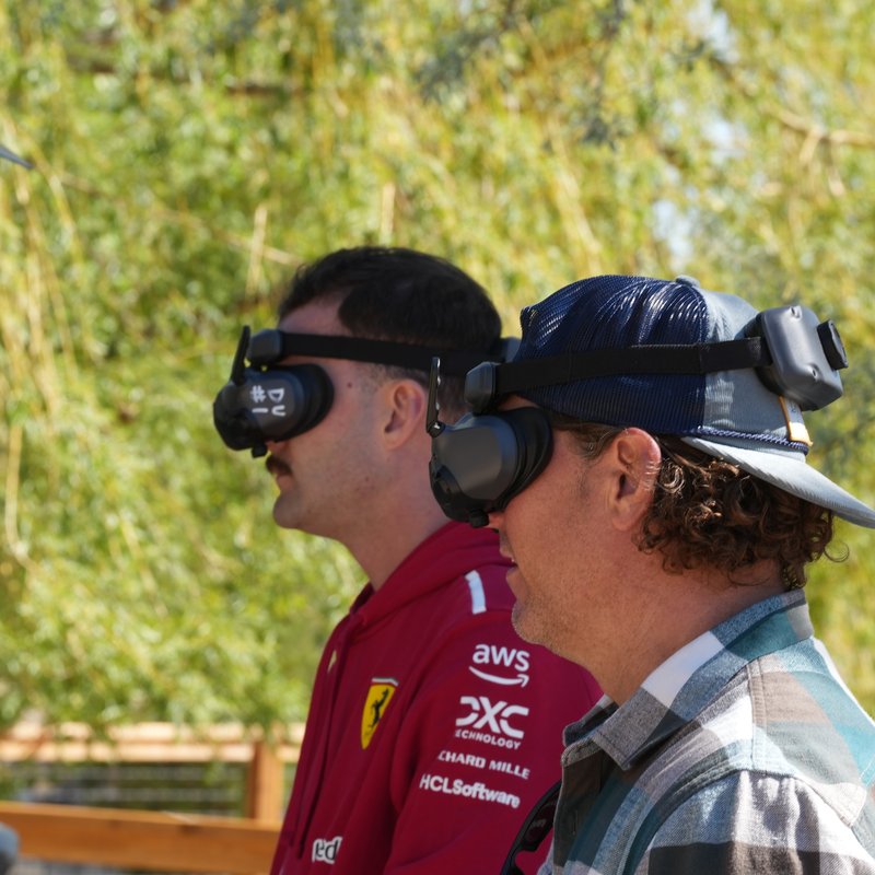 Two coworkers flying with FPV goggles, showing how peers motivate employees to become drone pilots